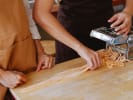 Team Building Cooking Class - Pasta Competition: close up of two women making pasta with pasta machine