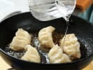 Cooking Class - Handmade Vegetable Dumplings in Tulsa: cooking gyoza dumplings in a pan with a splash of water