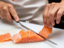 Cooking Class - Elegant Italian Dinner Party in Northern Virginia: chef in Cozymeal apron slicing fresh salmon fillet
