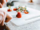 Cooking Class - British Pub Favorites in Downtown Dallas: Slicing fresh strawberries on cutting board – Close-up of someone’s hands carefully slicing ripe strawberries on a white cutting board.