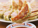 Cooking Class - Asian Takeout From Scratch: dumplings on a chopstick being dipped into sauce