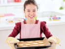 Cooking Class - Gluten-Free Confections for Young Bakers in Boston Proper: girl with a n apron, cooking mittens and a tray of freshly baked langue de chat cookies