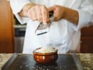 Cooking Class - Iconic French Cuisine Fare: grating gruyere cheese over a pot of onion soup