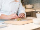 Cooking Class - Southeast Asia Delights - Date Night in Northern Virginia: Chef assembling fresh spring rolls â€“ A chef carefully wrapping spring rolls on a wooden cutting board with fresh ingredients.