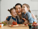 Cooking Class - Tasty Traditions – Family Fun in Manhattan: mom hugging two daughters while in kitchen aprons