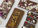 Cooking Class - Chocolate Making and Pairing in Columbus, OH: overhead view chocolate bar with toppings white backdrop