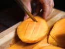 Cooking Class - Vibrant Vegan: person dicing mango on a wooden cutting board