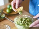 Team Building Cooking Class - Handmade Guacamole Competition: person dipping tortilla chip in a fresh bowl of guacamole
