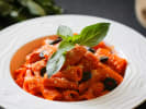 Cooking Class - Rustic Pasta Three Ways in Northern Virginia: rigatoni pasta with aubergine and basil and Parmesan cheese garnish on a white plate