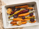 Cooking Class - Ribeyes to Galettes - Date Night in Downtown Dallas: Rainbow carrots roasting in a white pan – Multicolored carrots roasting in a white baking dish, garnished with herbs and resting on a beige towel.