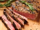 Cooking Class - Flame-Grilled Flavor in Northern Suburbs: Grilled skirt steak sliced on wooden board – Medium-rare skirt steak sliced into strips and topped with fresh herbs, resting on a wooden cutting board.