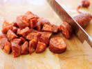Online Cooking Class - Perfect Spanish Paella: slicing chorizo on a wooden cutting board
