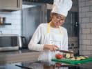 Cooking Class - Teens Take on the Culinary World in Downtown Dallas: a teenage girl is chopping vegetables while wearing an apron