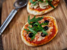 Kids' Cooking Class - Pizza Party for Young Chefs: two mini pizzas on a wooden board with olives, cheese and arugula