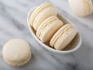 Cooking Class - Macaron Dreams in Manhattan: White macarons on marble surface â€“ Three vanilla macarons placed neatly on a white marble slab with a shallow dish of more in the background.