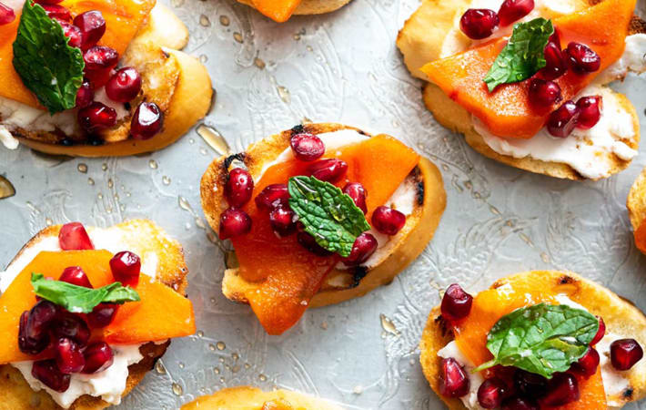pomegranate persimmon crostini are colorful, bite sized vegan christmas appetizers