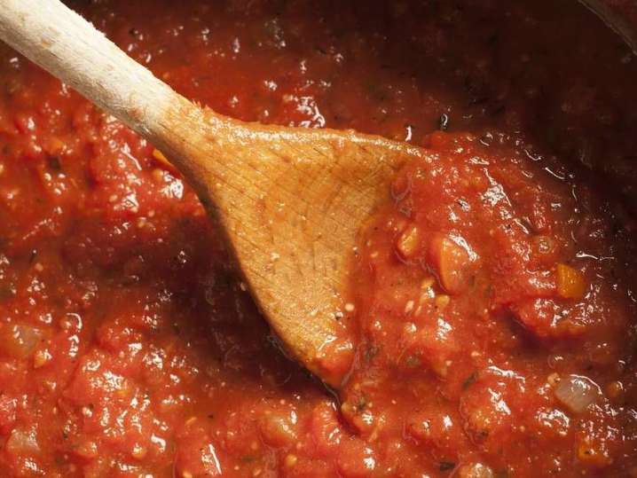 stirring marinara sauce in a pot with a wooden spoon Shot