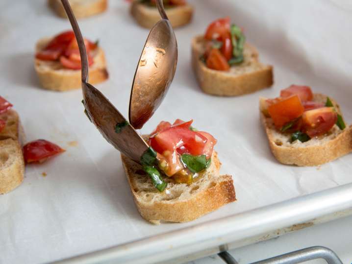 close-up of spoons plating bruschetta on a baking tray Shot