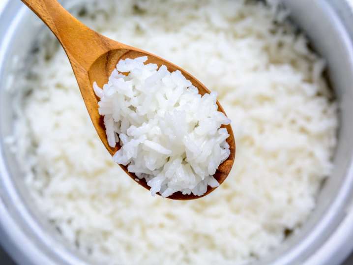 spoon full of basmati rice over a rice cooker Shot