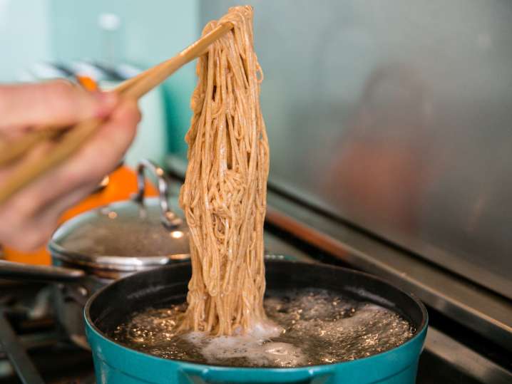 chef stirring ramen noodles in a pot on the stove Shot