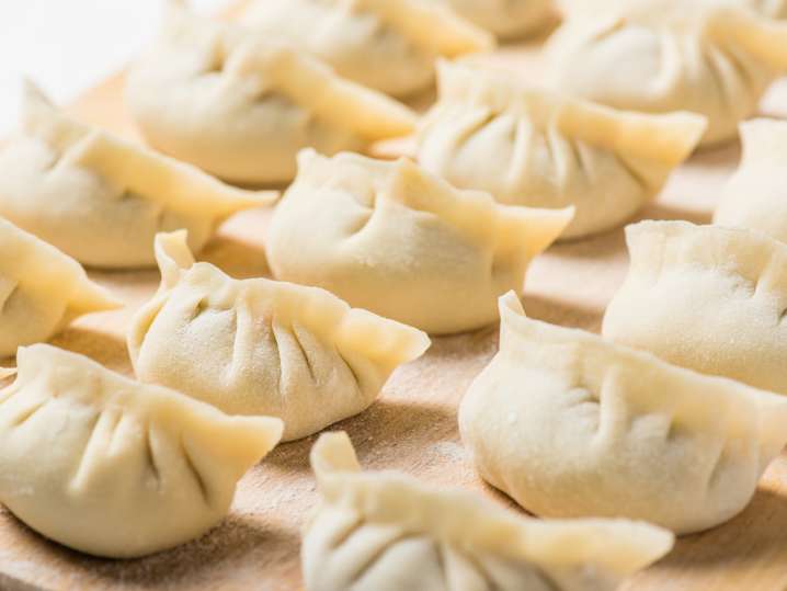 uncooked potsticker dumplings on a cutting board Shot