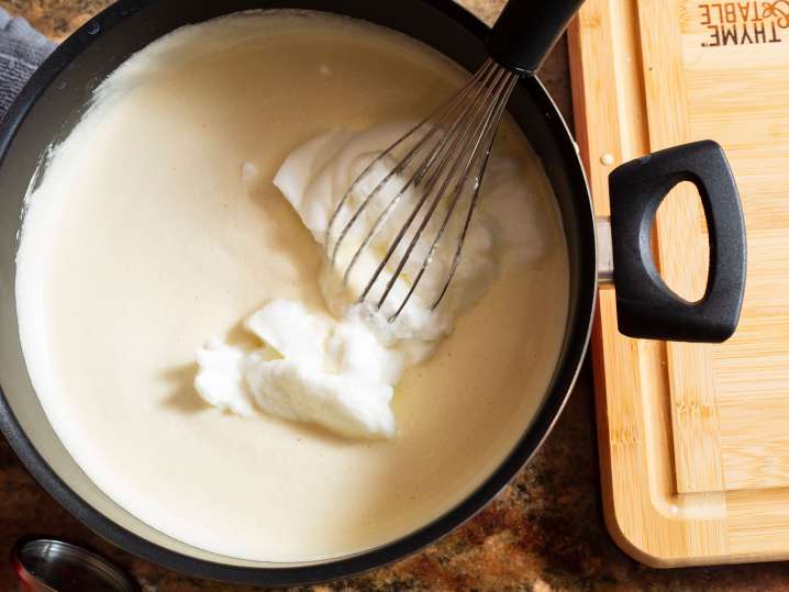 a whisk stirring mornay sauce in a pot Shot