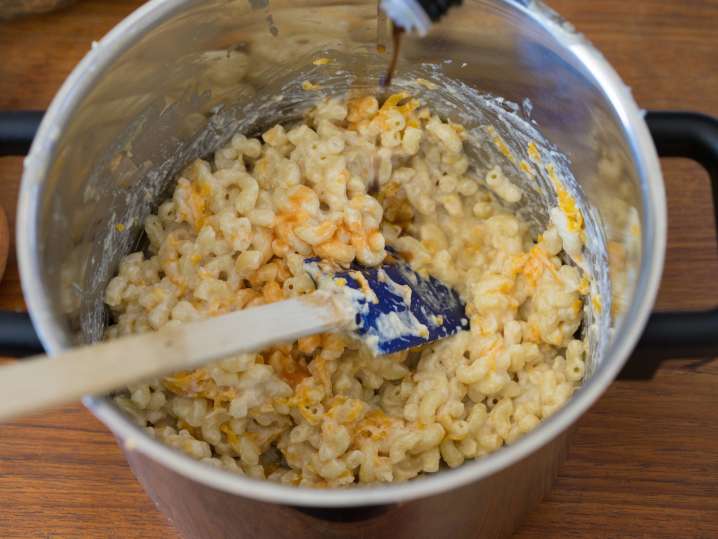 elbow pasta being stirred with mornay sauce and shredded cheese Shot