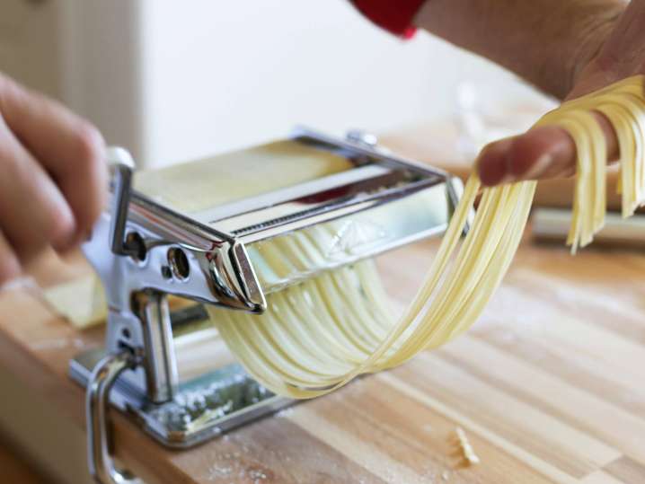 chefs hands rolling a sheet of fresh pasta through a pasta cutter Shot