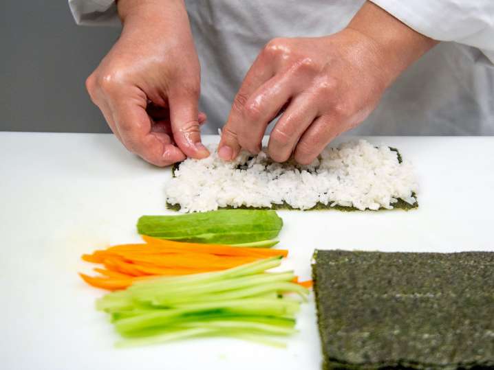 chef's hands preparing a sushi roll Shot