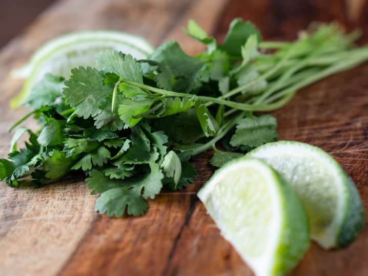 cilantro and lime wedges on a cutting board Shot