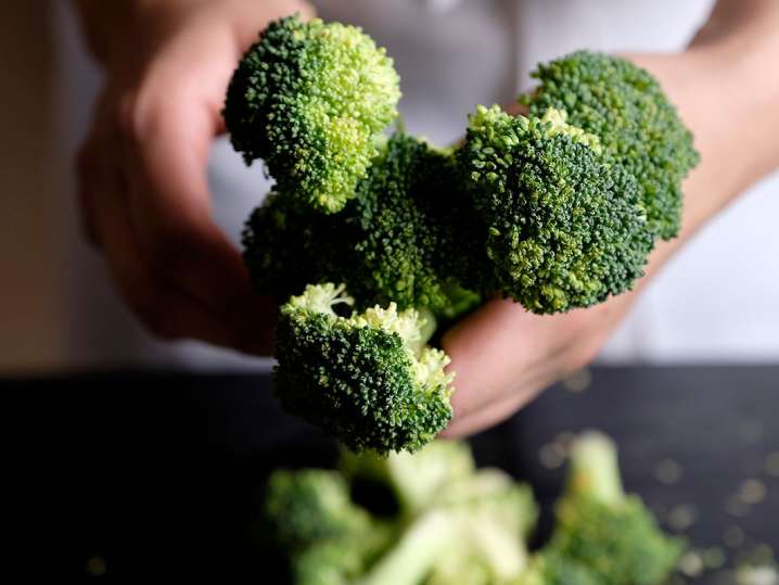 chef's hands holding broccoli Shot