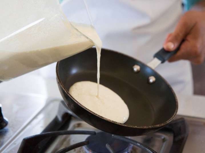 chef pouring crepe batter into a frying pan Shot
