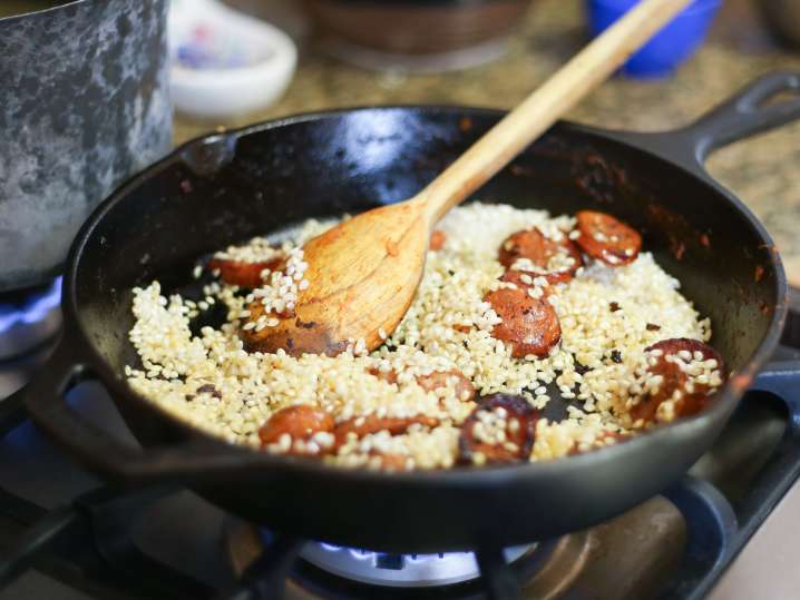 wooden spoon stirring paella rice with sausage Shot