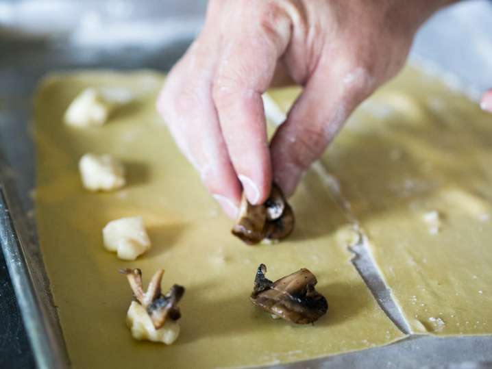 chef filling ravioli sheets with cheese and mushrooms Shot