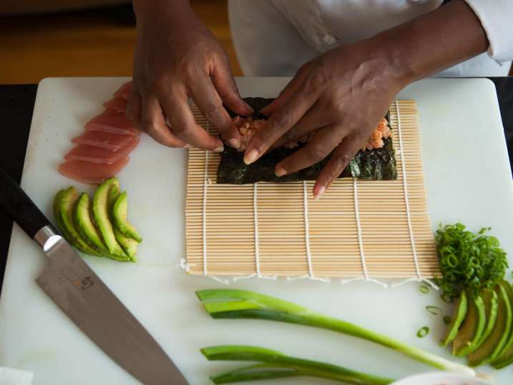 chef's hands preparing a tuna roll on a bamboo mat Shot