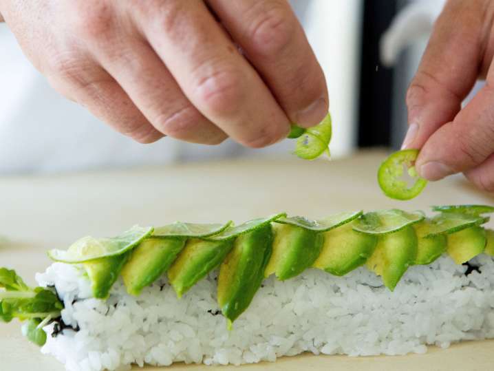 putting avocado slices on a caterpillar roll Shot