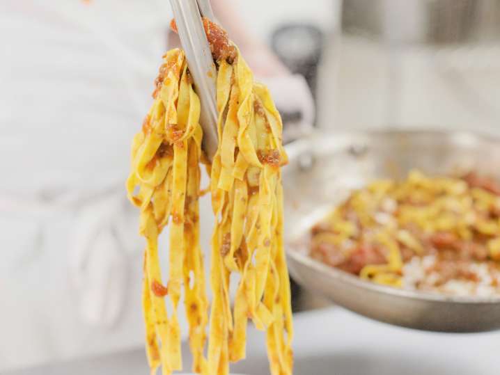 chef plating homemade pappardelle and bolognese sauce Shot