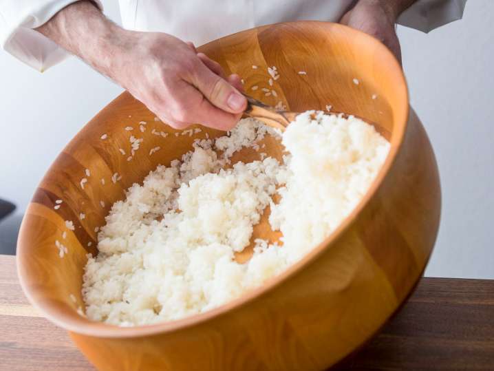 chef stirring sushi rice in a bamboo bowl Shot