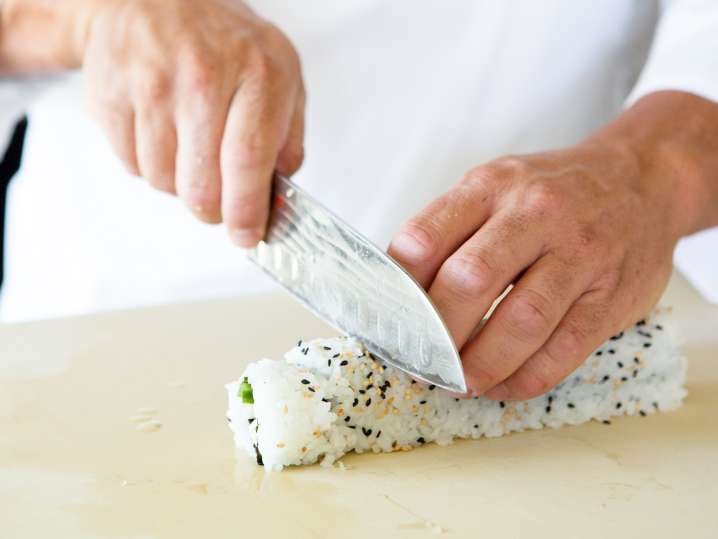 chef slicing california sushi roll Shot