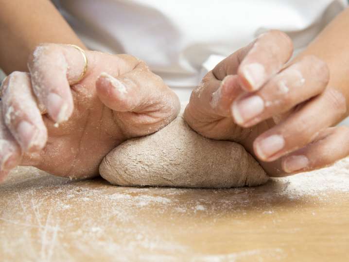 chef kneading fresh pizza dough on a floured work surface Shot