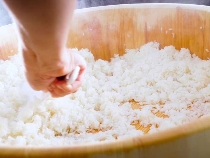 chef stirring sushi rice in a bamboo bowl Shot