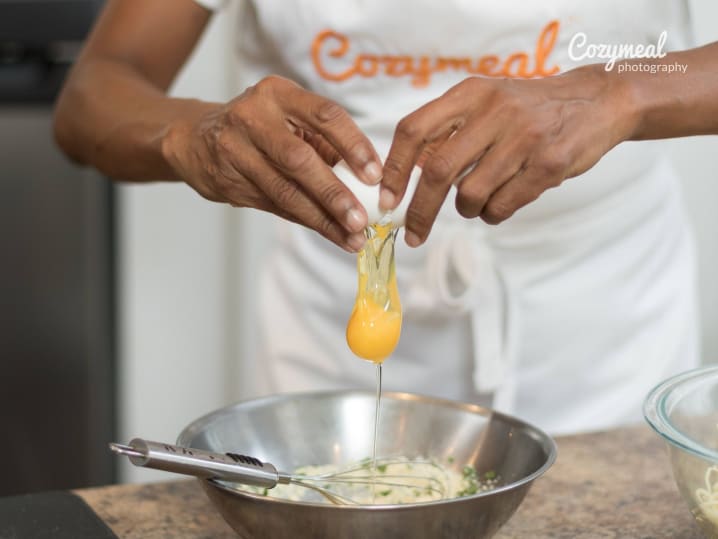 Cracking an egg into a mixing bowl for pasta dough preparation.