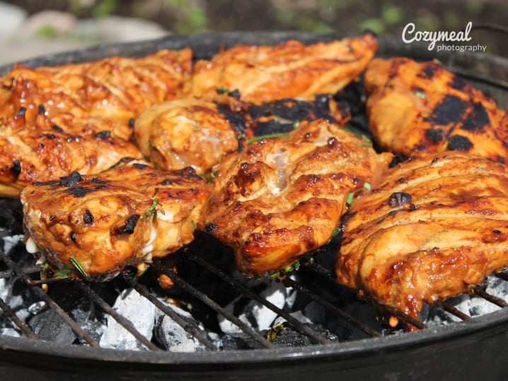 Grilled Peruvian spice-rubbed chicken thighs with charred edges, sizzling on the grill.