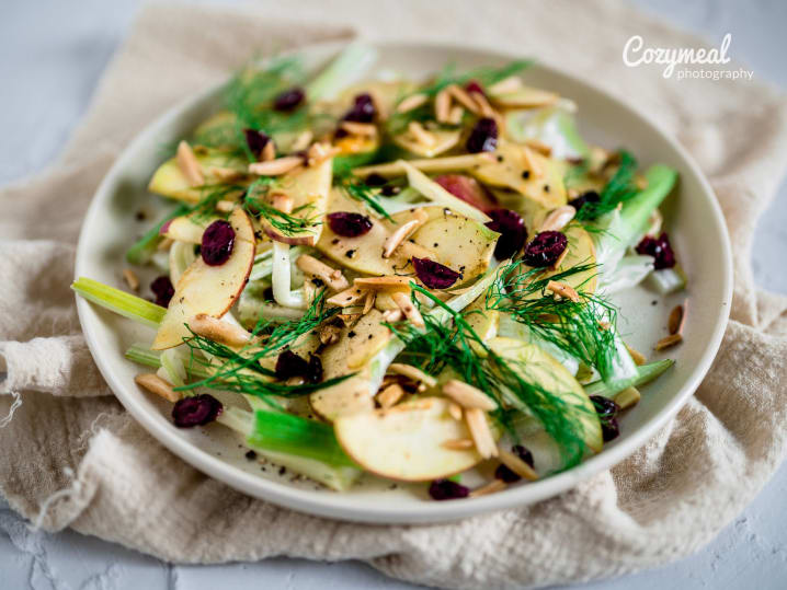 Apple and fennel salad with whole-grain mustard vinaigrette, garnished with herbs.