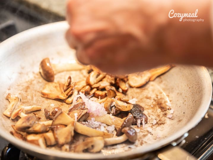 SautÃ©ing a mix of wild mushrooms in a skillet with herbs.