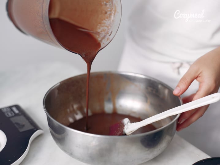 Pouring maple custard mixture into ramekins from a mixing bowl.