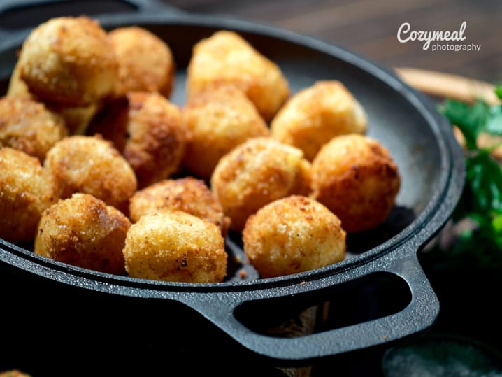 Golden truffled pommes dauphine served in a cast iron skillet.