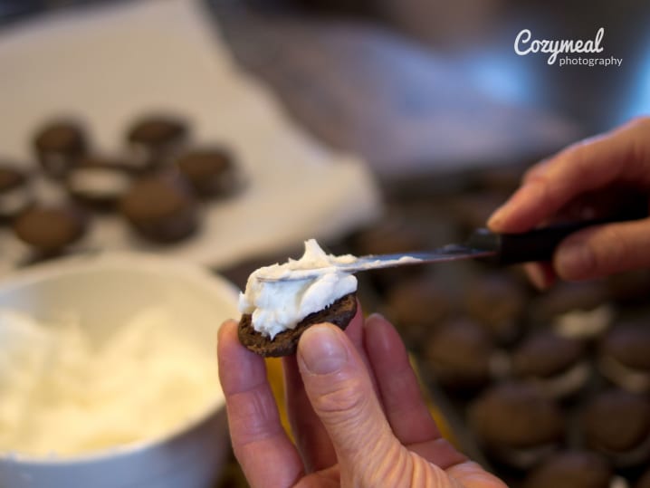 Piping marshmallow cream filling onto a chocolate cookie for whoopie pies.