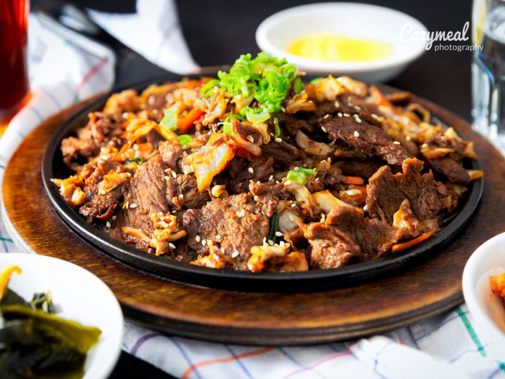 Bowl of grilled bulgogi beef garnished with scallions and sesame seeds.