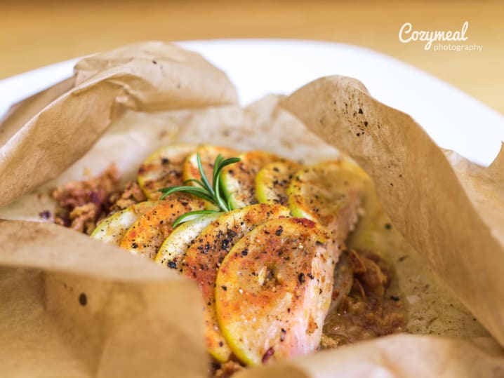 Baked salmon en papillote with herbs and sliced vegetables, served in parchment.